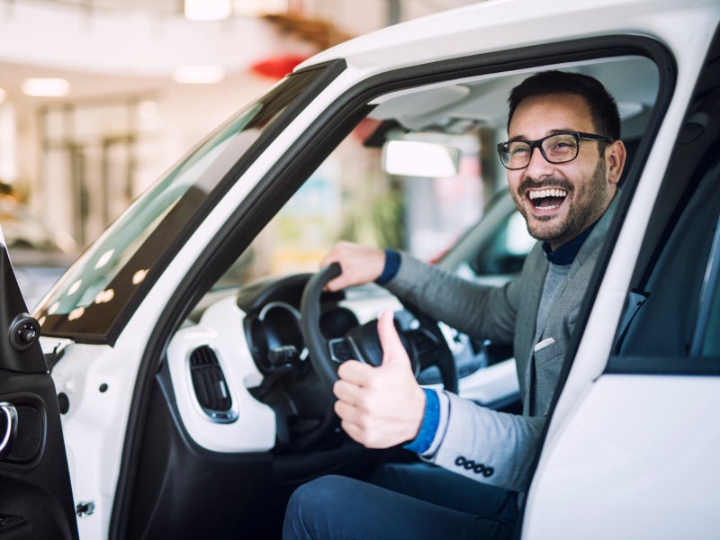 Man sitting in vehicle, giving a thumbs up with a smile